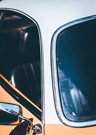Close-up of vintage car windows with chrome trim and orange paint