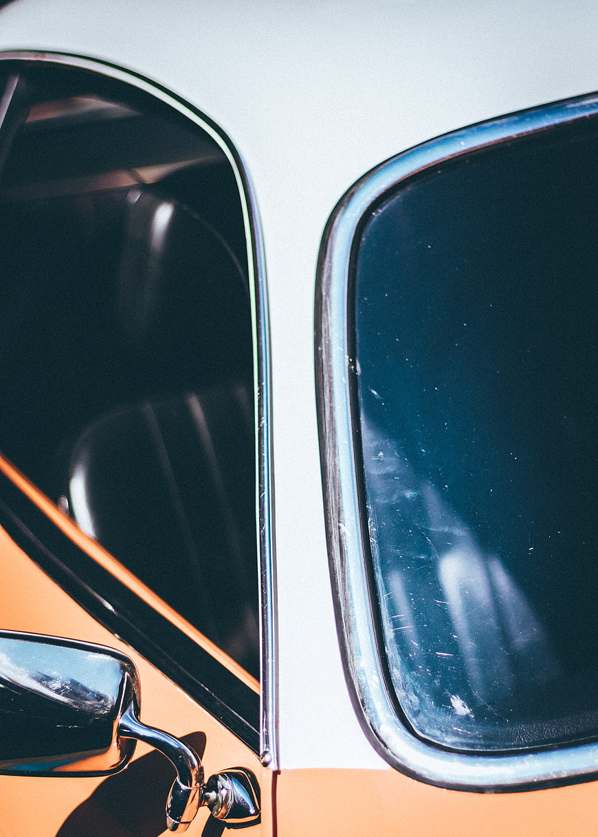 Close-up of vintage car windows with chrome trim and orange paint