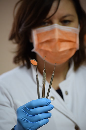 Female Dentist Holding Dental Instruments in Blue Gloves