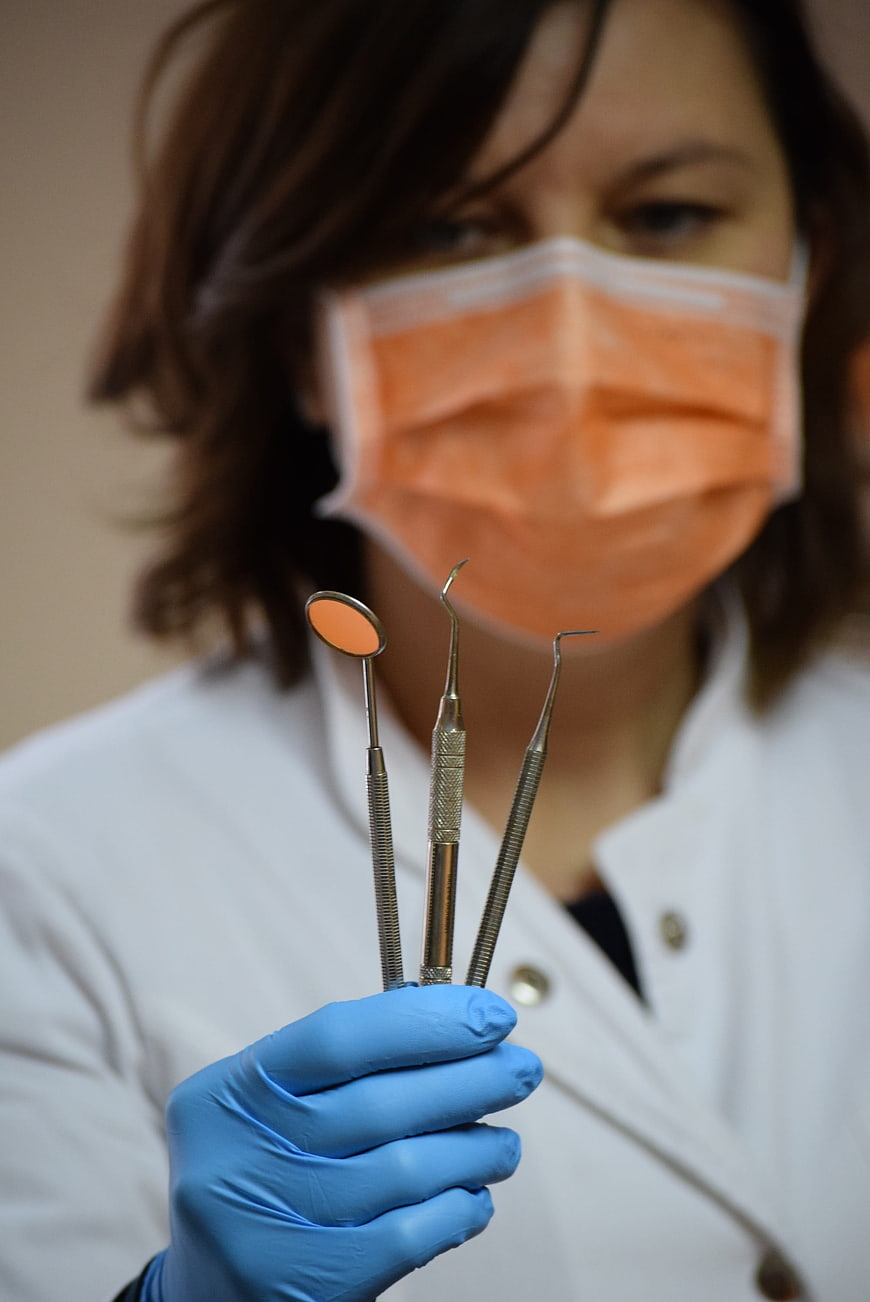 Female Dentist Holding Dental Instruments in Blue Gloves