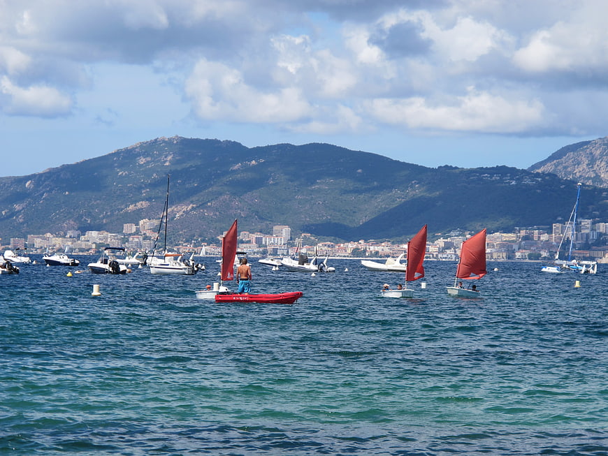 Sailboats with red sails in a coastal bay with mountains