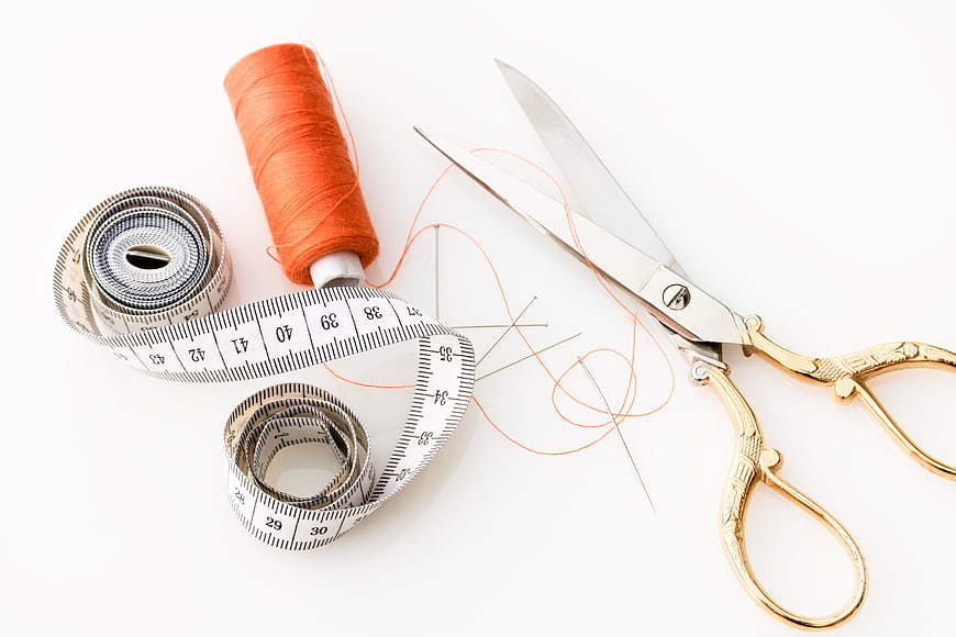 Sewing supplies with orange thread, scissors, and measuring tape