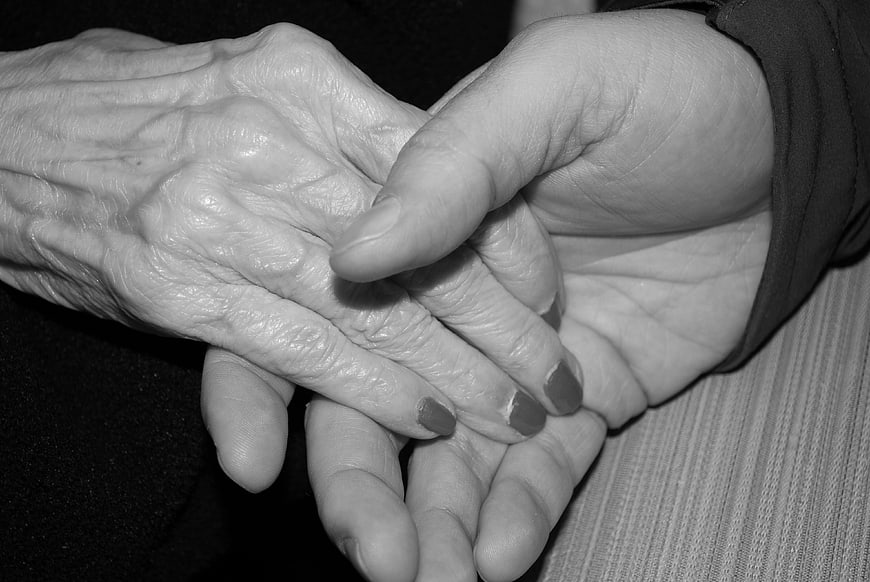 Black and white photo of elderly hands holding younger hands