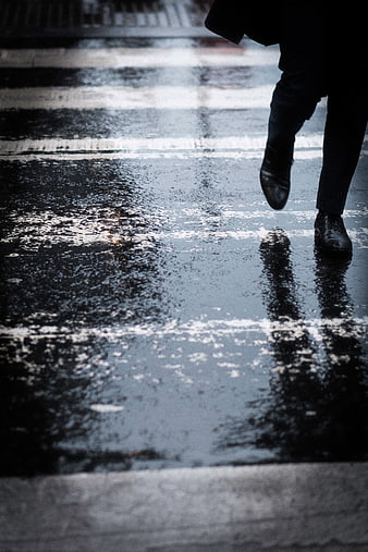 Person walking on wet street crosswalk in rain