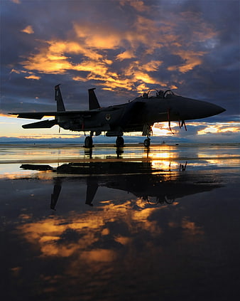 Military Fighter Jet Silhouette on Wet Runway at Sunset