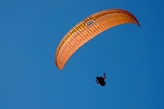 Orange Paraglider Flying Against Clear Blue Sky