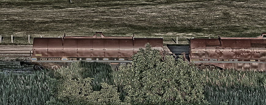 Rusty freight train cars on rural tracks