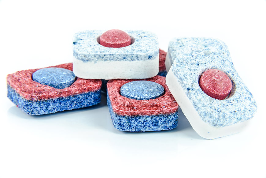 Colorful dishwasher detergent tablets on white background