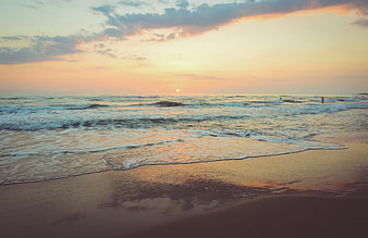 Serene Sunset Beach with Gentle Waves and Surfers