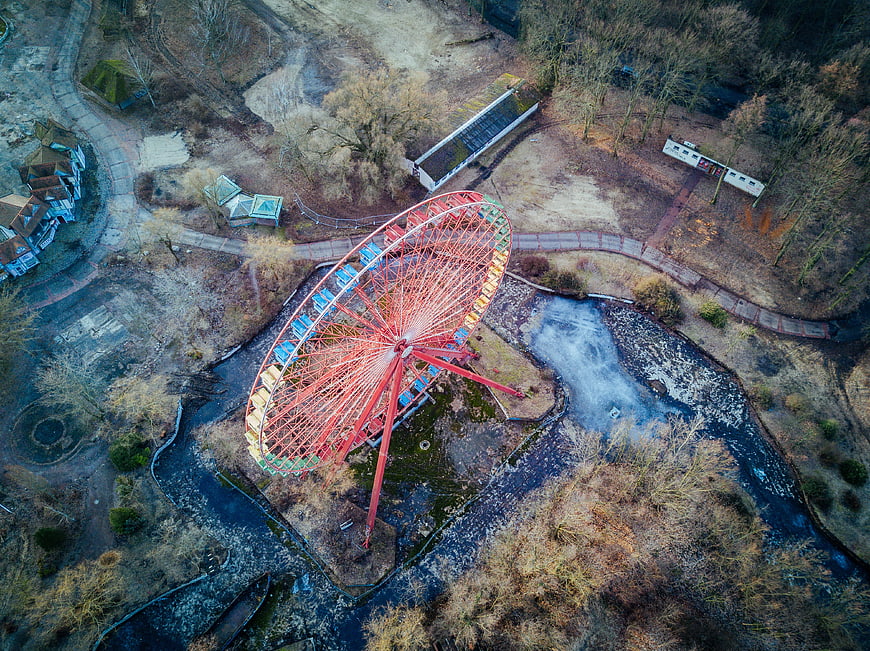Aerial view of abandoned red ferris wheel in overgrown park