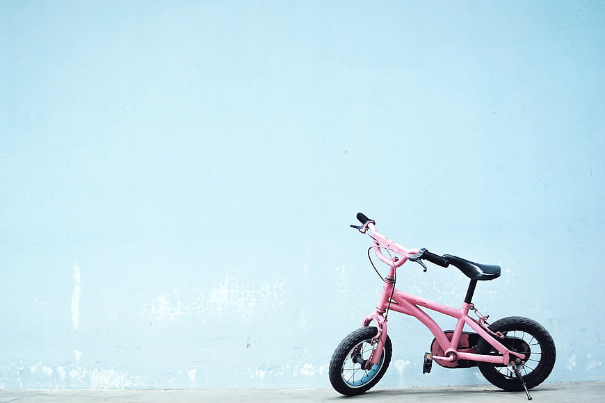 Pink Kids Electric Bike Against Light Blue Wall