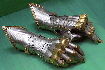 Medieval silver and gold armor gauntlets on green background