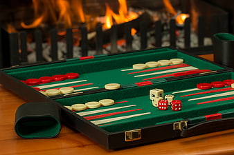 Backgammon board with dice and chips set against a warm fireplace background