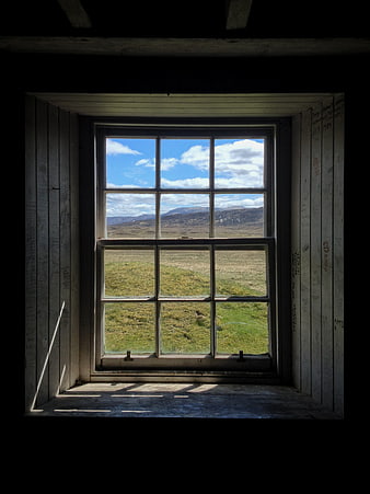 Rustic wooden window frame looking out onto a scenic Scottish countryside landscape
