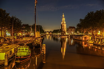 Night view of Amsterdam canal with Westerkerk tower and boats