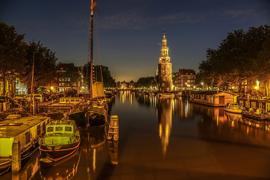 Night view of Amsterdam canal with Westerkerk tower and boats