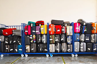 Colorful Suitcases Stacked on Blue Carts in Airport Warehouse