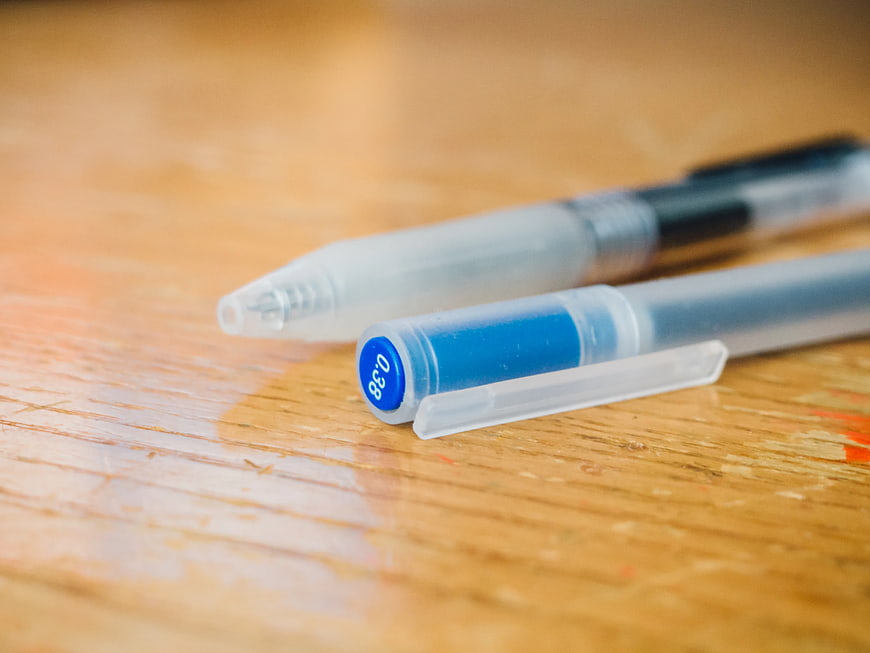 Close-up of Blue and Black Pens on Wooden Desk
