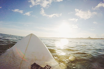 Surfboard Nose in Ocean Water with Blue Sky and Sun