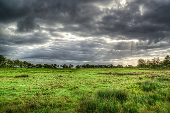 Dramatic Storm Clouds Over Green Meadow with Sunbeams