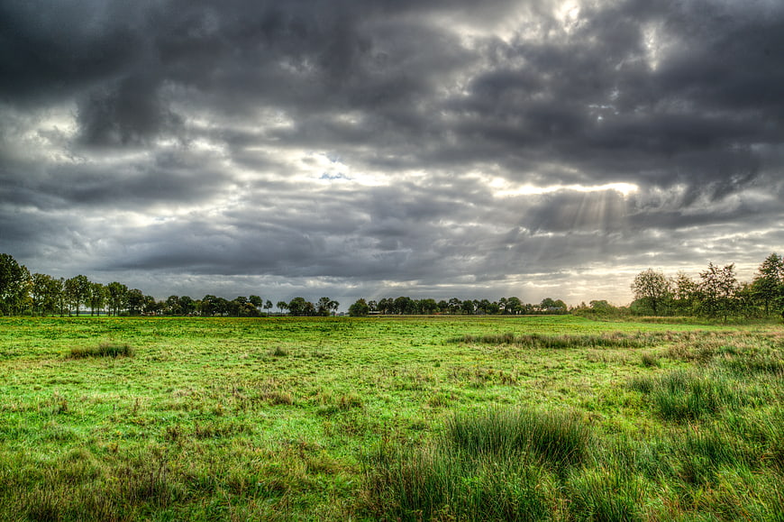 Dramatic Storm Clouds Over Green Meadow with Sunbeams