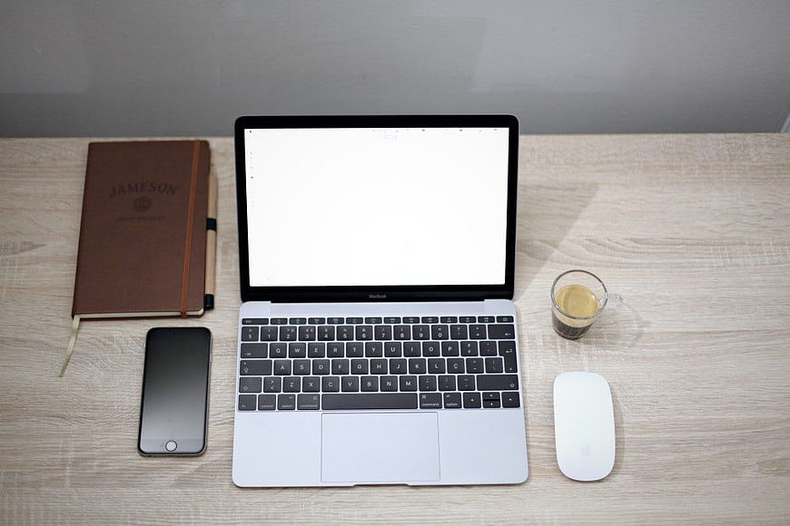 Top-down view of laptop, notebook, and coffee on desk