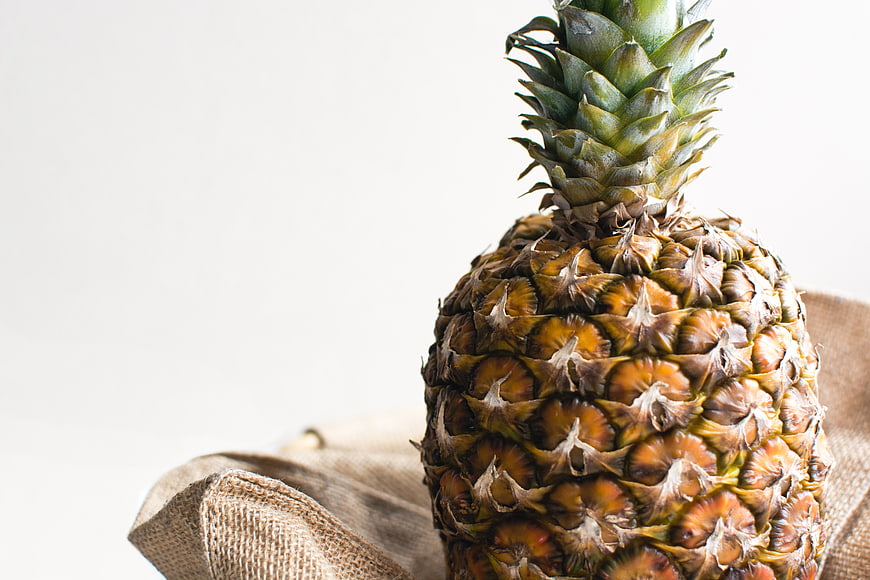 Close-up of fresh pineapple on burlap with white background