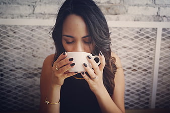 Woman drinking coffee with eyes closed in cafe