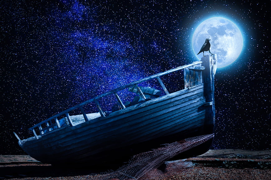 Old wooden boat on shore under full moon and starry night sky