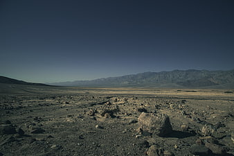Barren rocky desert landscape with distant mountains and clear sky