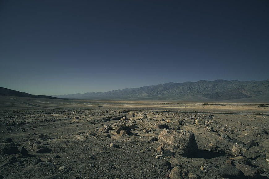 Barren rocky desert landscape with distant mountains and clear sky