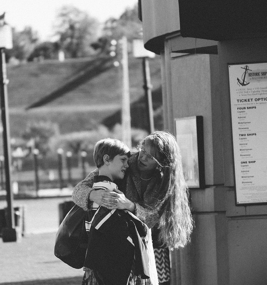Black and white photo of woman hugging boy outdoors