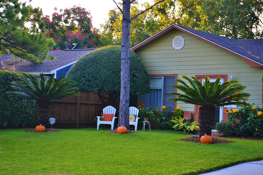 Cozy suburban home with autumn pumpkins and green lawn