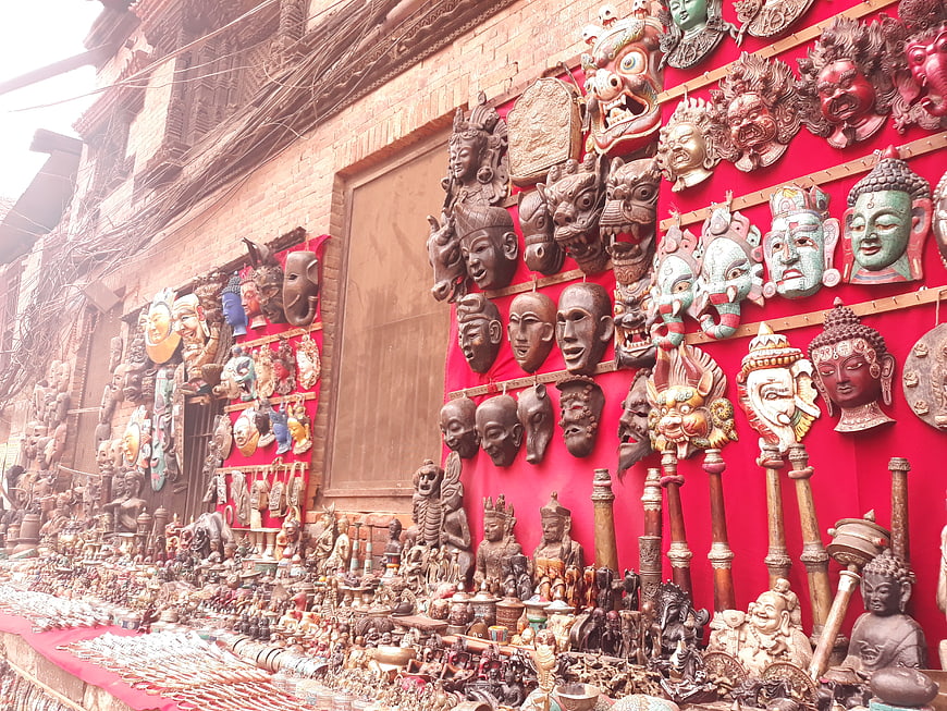 Traditional wooden masks and statues displayed in a Bhaktapur market