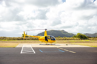 Yellow Helicopter on Landing Pad with Mountain Background