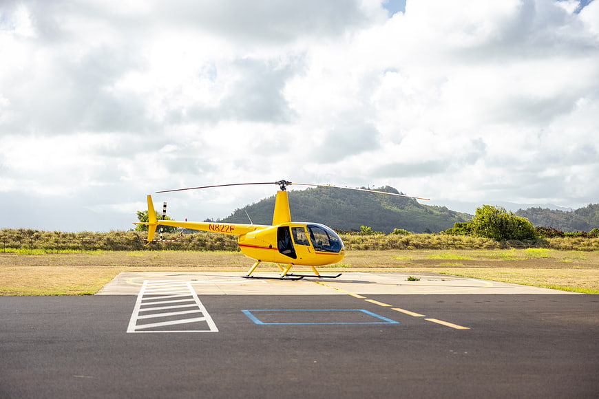 Yellow Helicopter on Landing Pad with Mountain Background