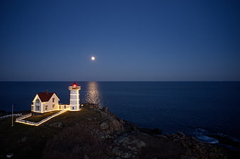 Lighthouse on Rocky Coast at Night with Moon