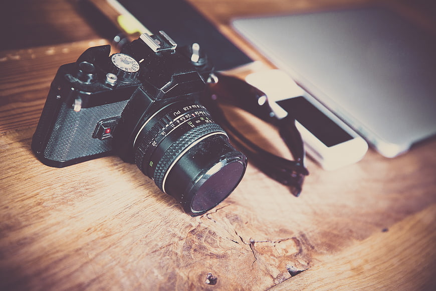 Vintage Film Camera on Wooden Desk with Laptop and Smartphone