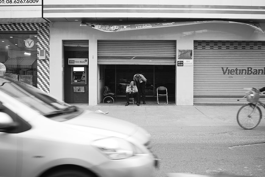 Street Photography of Men Resting Outside VietinBank Branch in Black and White