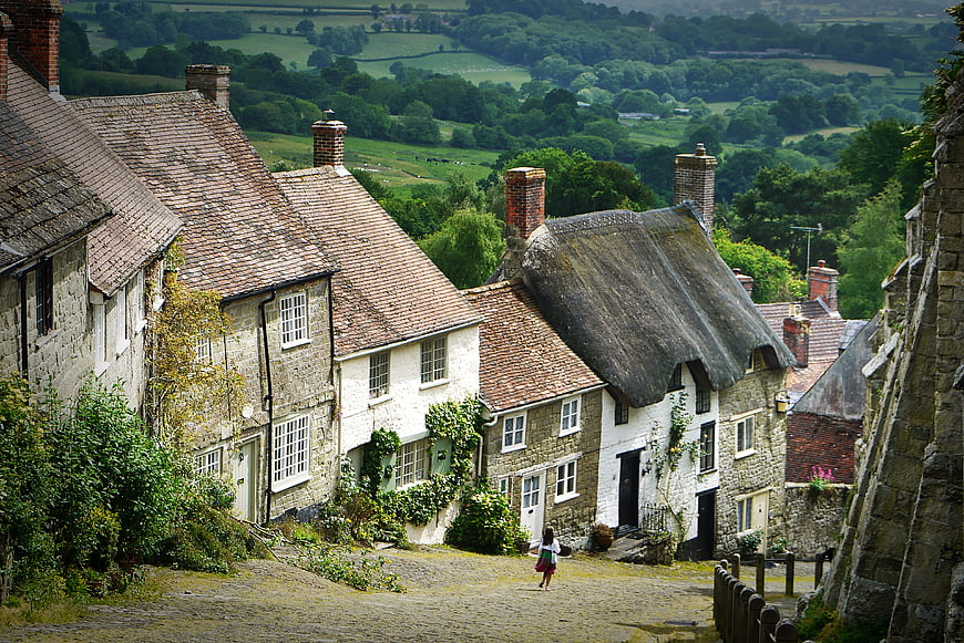 Child walking down cobblestone street in historic English village