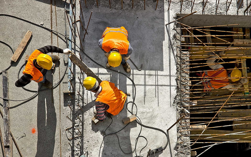 Aerial View of Construction Workers in Orange Vests and Yellow Hard Hats