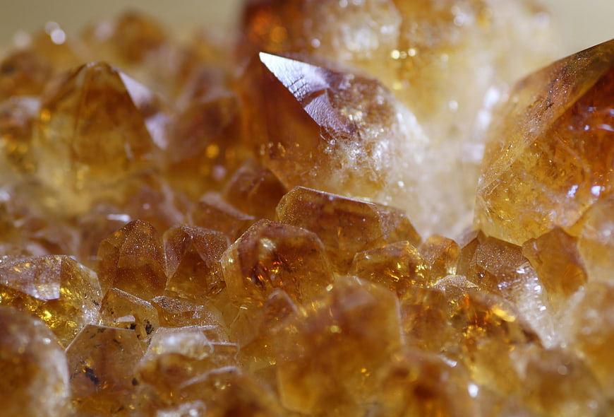Macro shot of golden citrine crystals with sharp facets and warm amber tones