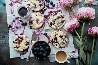 Flat lay of blueberry cookies, coffee, and pink peonies