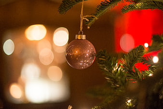 Close-up of a pink Christmas bauble on a tree with bokeh lights