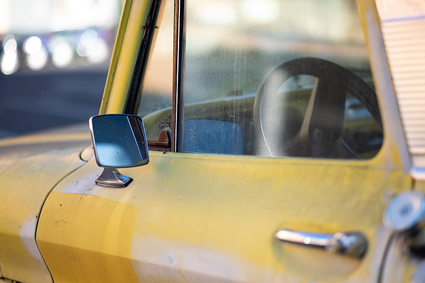 Close-up of vintage yellow car door and side mirror