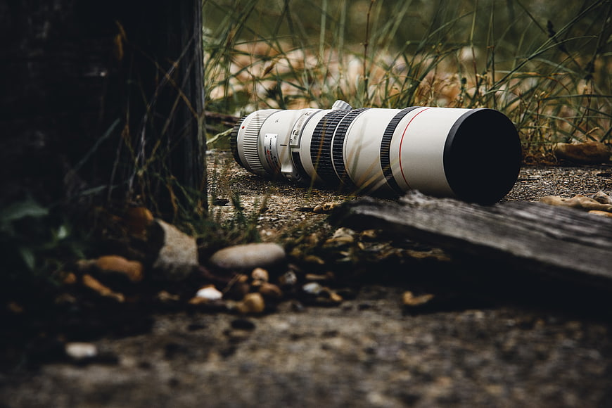 White Telephoto Camera Lens on Gravel Path in Nature