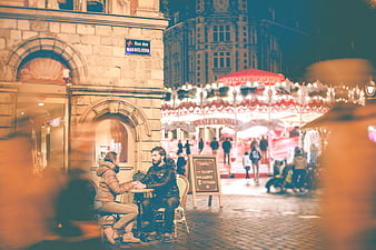 Couple at Outdoor Cafe with Carousel in Background at Night