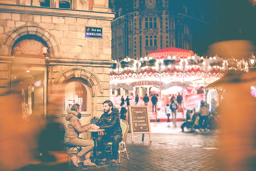 Couple at Outdoor Cafe with Carousel in Background at Night