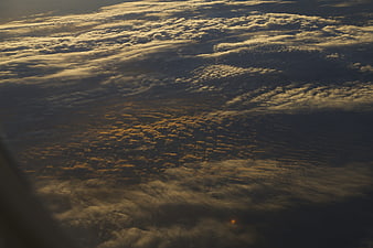 Aerial view of textured clouds at sunset from airplane window