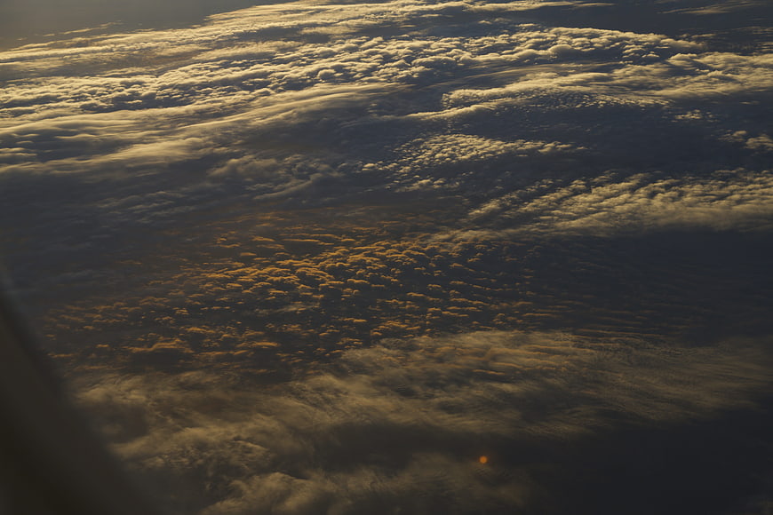 Aerial view of textured clouds at sunset from airplane window
